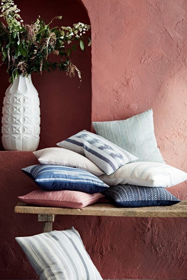stack of cushions on rustic timber bench against terracotta feature wall from west elm