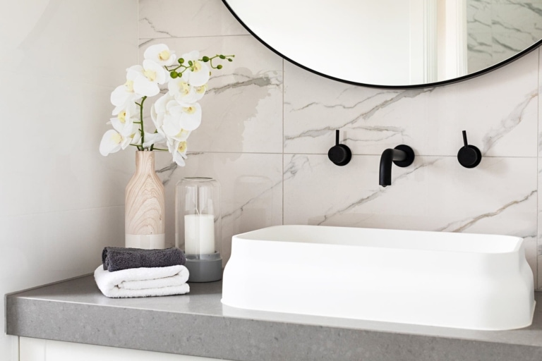 big w fake orchid in white bathroom with black taps