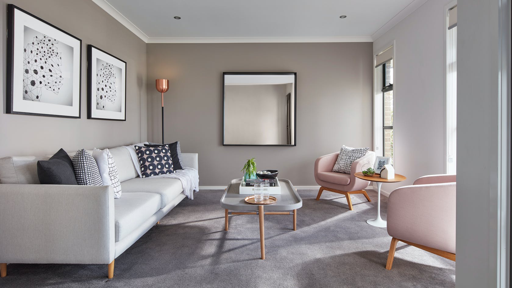 formal living room styling with mirror on wall pink armchairs and grey sofa
