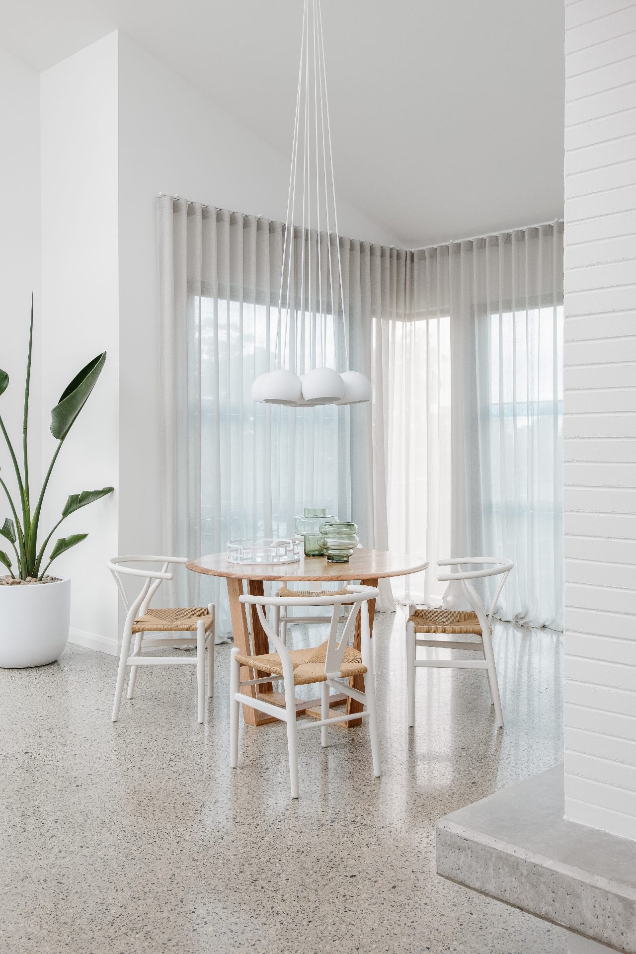 polished concrete floor dining room with round oak timber table and woven rattan chairs oz design