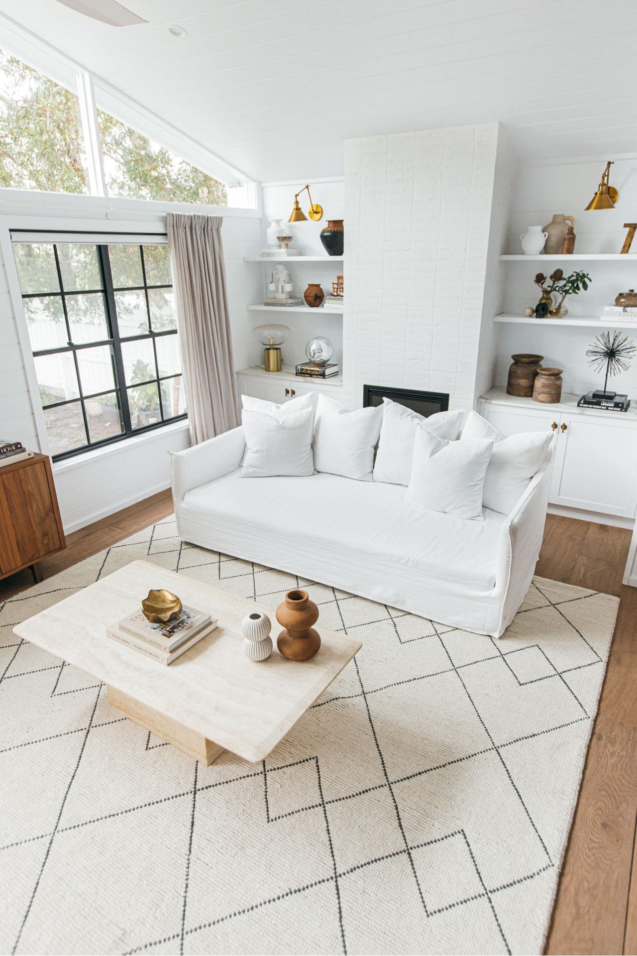 black and beige diamond floor rug in living room with white slip cover sofa