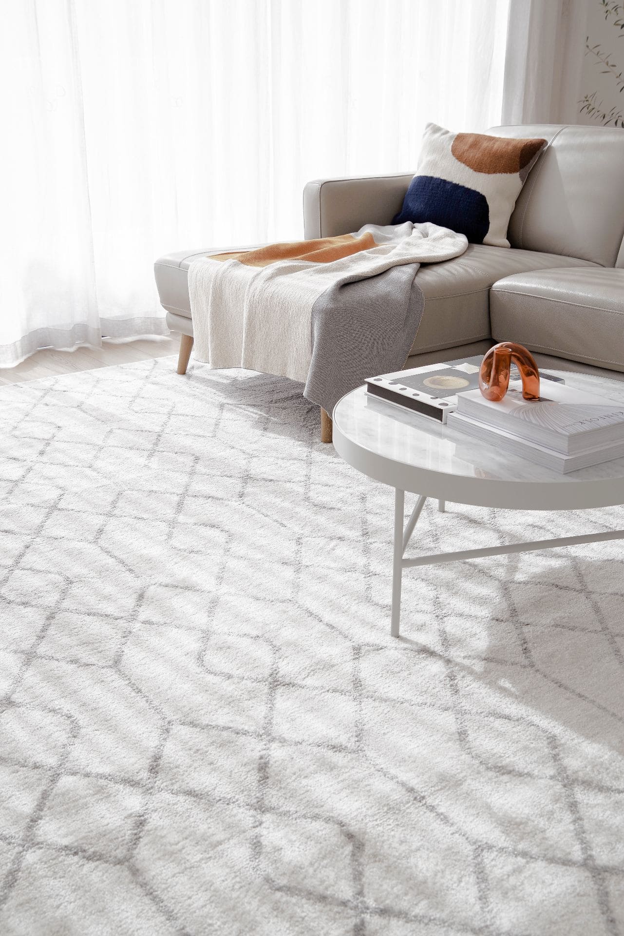 grey and white diamond floor rug in living room with white sheer curtains