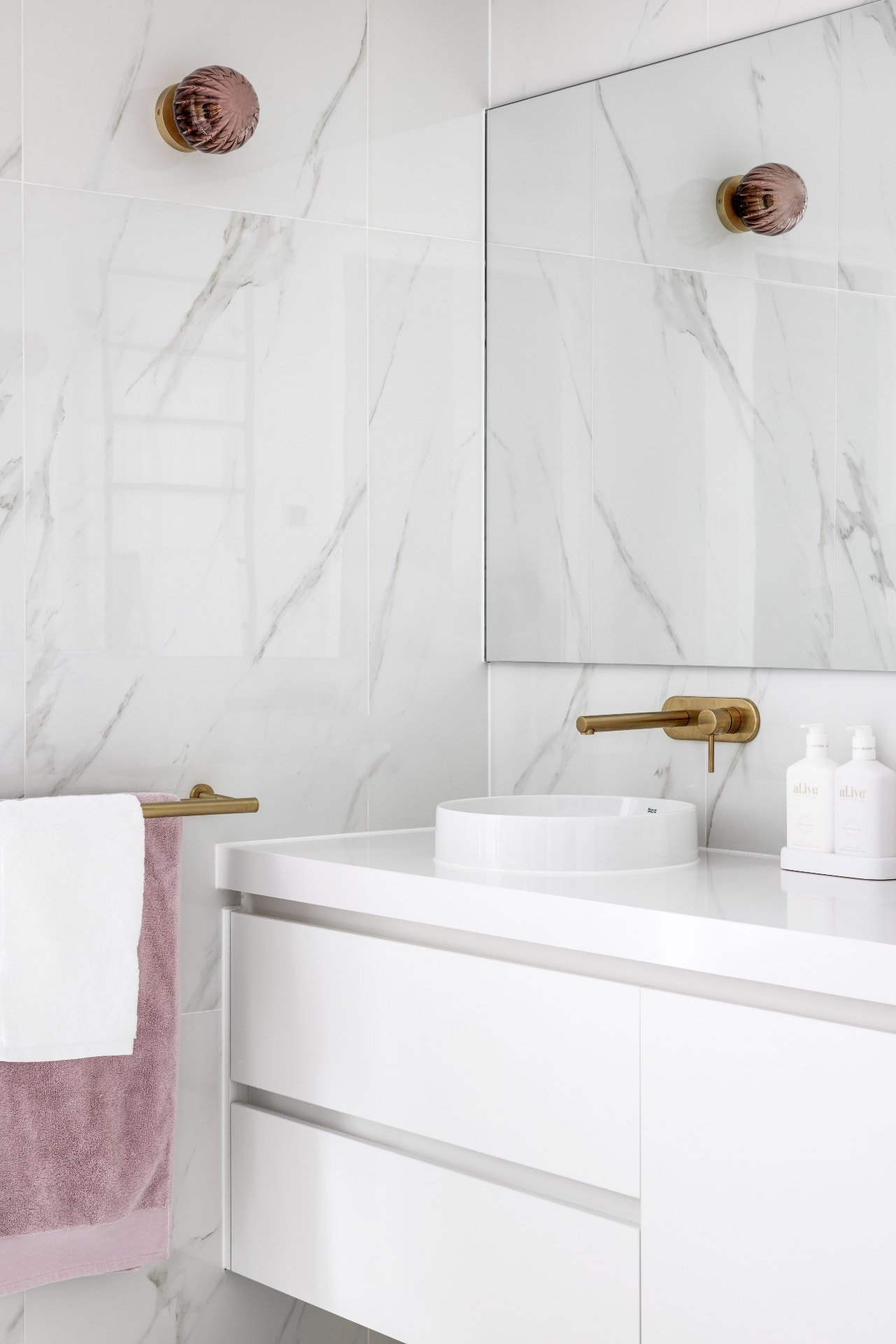 bathroom with white marble wall tile brass tapware pink glass wall light