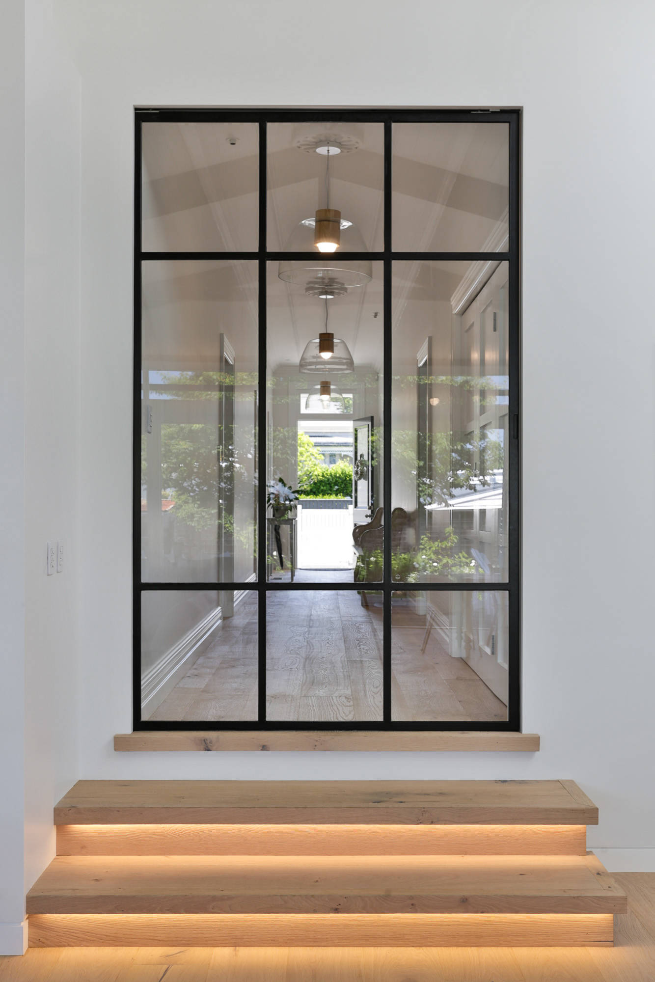 black frame glass door in long hallway with oak floors