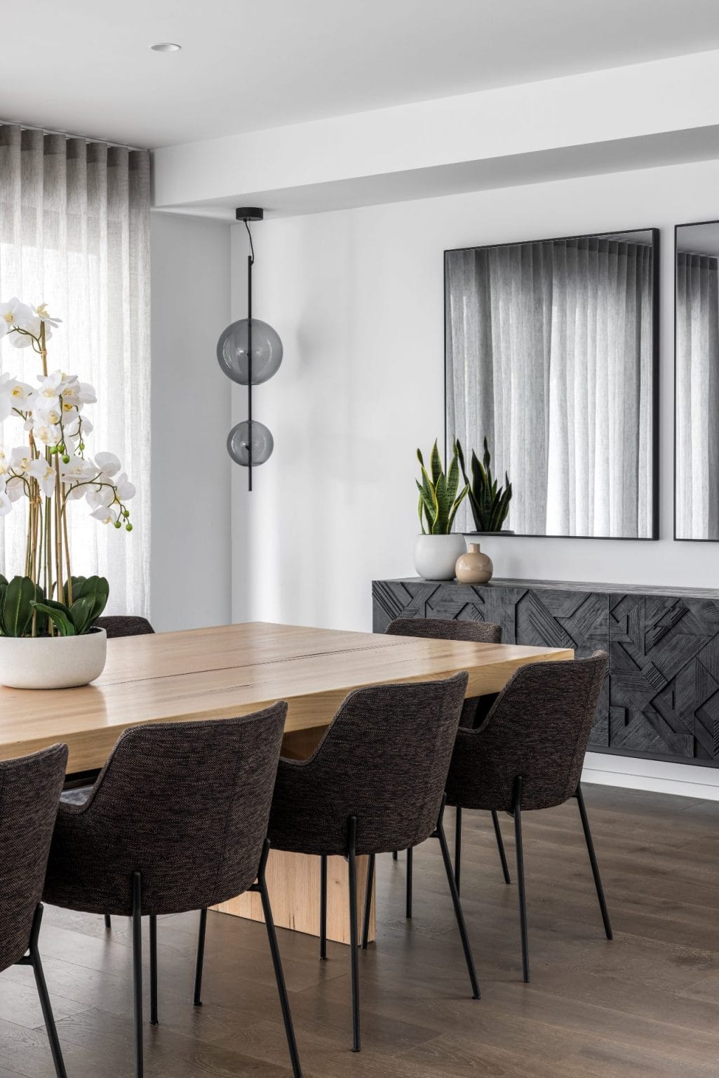 contemporary luxe dining room with black geometric sideboard tinted mirrors and round tinted glass pendant light