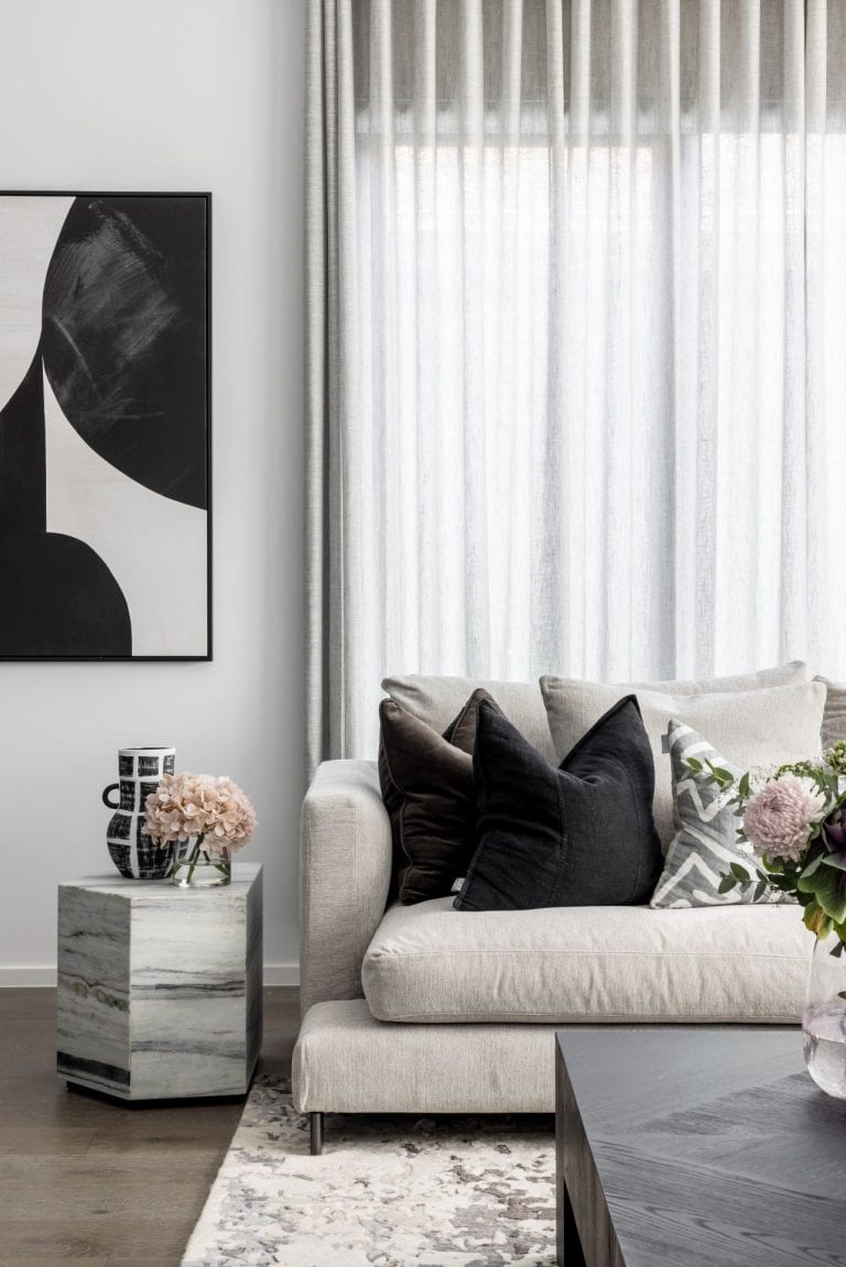 grey sofa with black cushions and marble geometric side table pink flowers