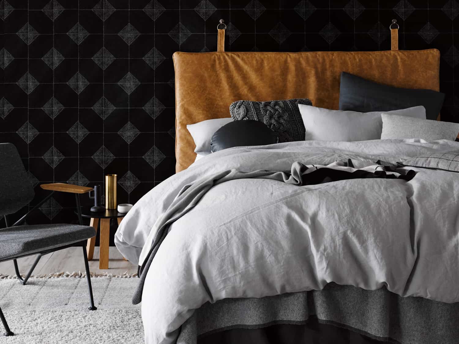heatherly design mans bedroom with tan leather bed and black feature wall