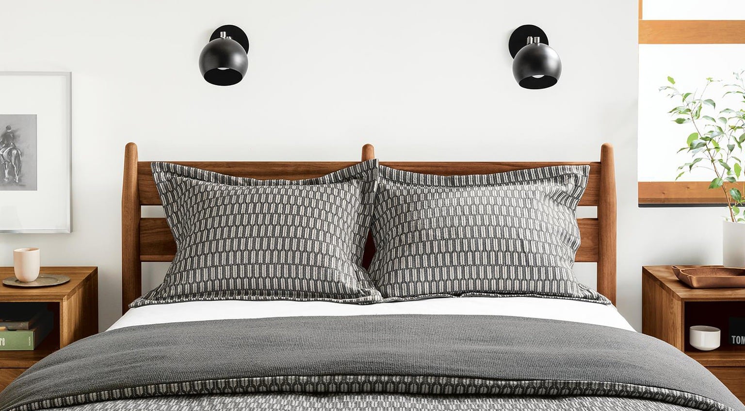 mans bedroom with timber bed frame and black and white pattern bedding
