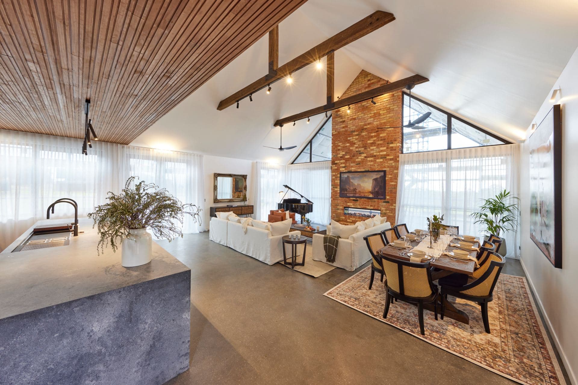 the block 2022 omar and oz open plan living and dining room with red brick fireplace