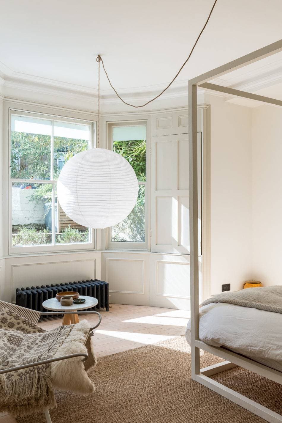 bedroom with four poster bed and round white paper lantern pendant light