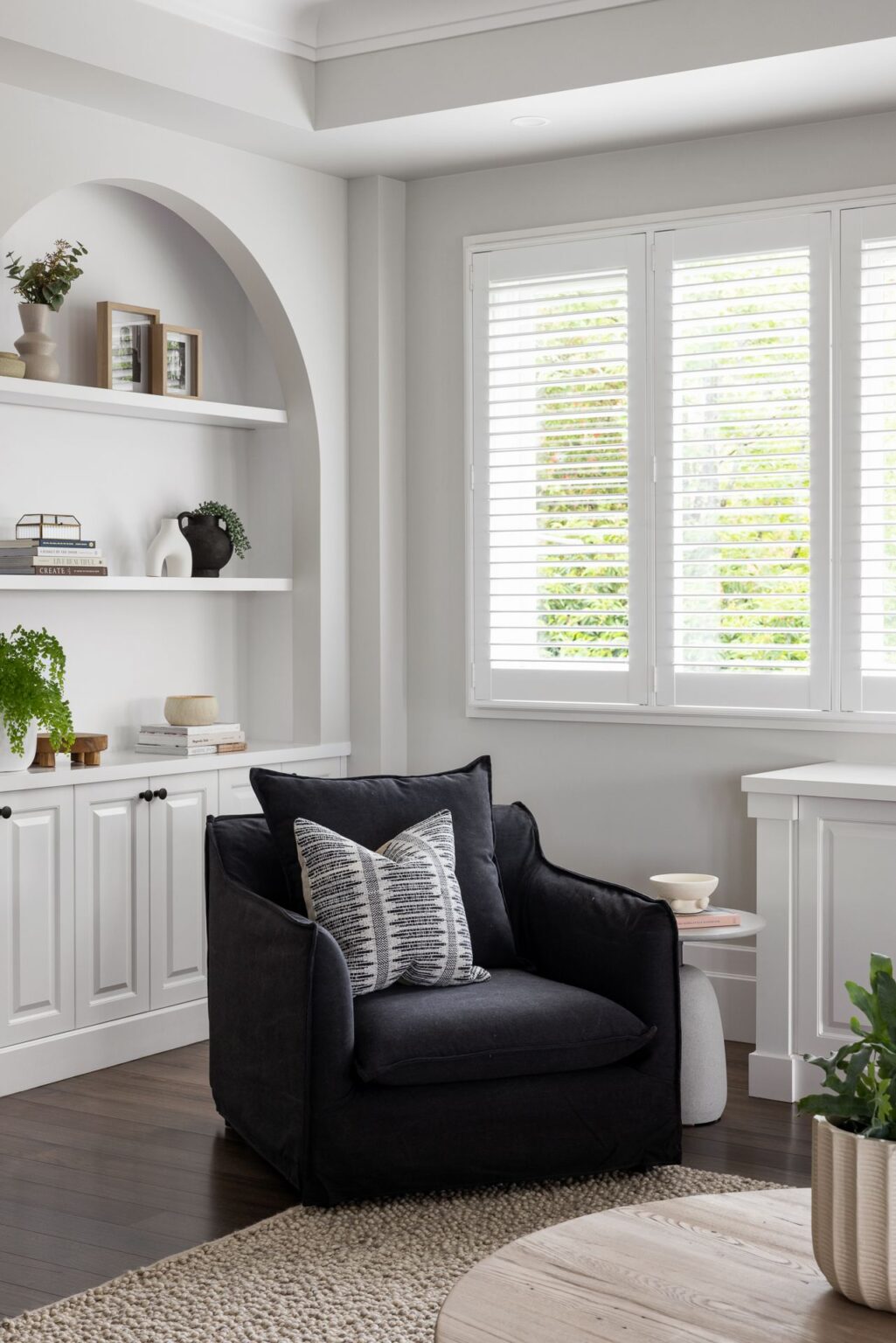 black slip cover sofa in modern country living room with walnut floors and arched shelving